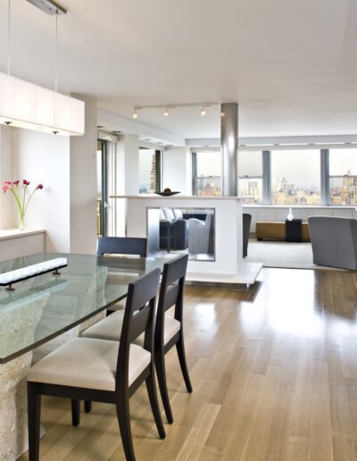 Modern and spacious apartment interior with a dining area, living space, and large windows showcasing city views.